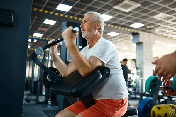Homem idoso, treino na máquina de exercícios no ginásio — Fotografia de Stock