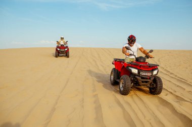 ATV 'deki kum tepelerinden iki yarışçı geliyor.