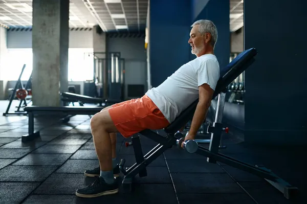 Egzersiz sonrası havluyla uğraşan yorgun yaşlı bir adam.