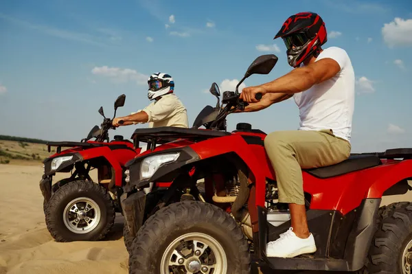 ヘルメットとメガネの男性は砂漠のatvに乗る — ストック写真