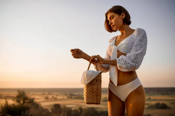 Mulher de lingerie branca segura cesta no campo — Fotografia de Stock