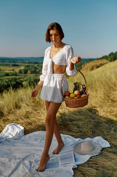 Sexy woman holds basket with fruits in the field — Stock Photo, Image