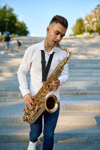 Saxofonista toca o saxofone em escadas no parque — Fotografia de Stock