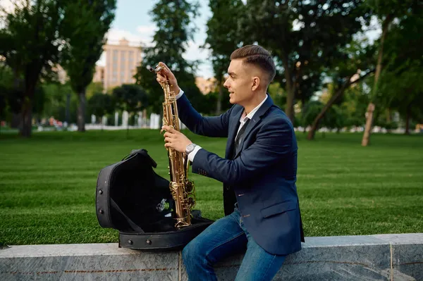 Saxofonista masculino tira o saxofone do caso — Fotografia de Stock