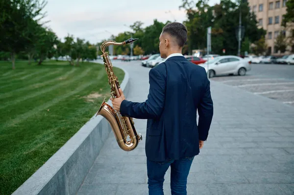 Saxofonista toca melodia no banco do parque da cidade — Fotografia de Stock