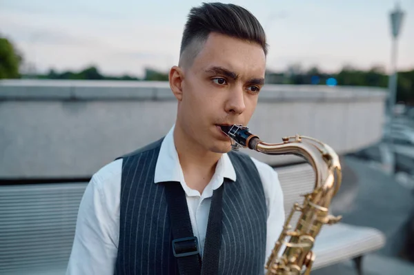 Saxofonist spielt Melodie auf Bank im Stadtpark — Stockfoto