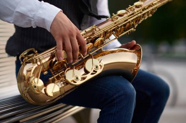 Saksafoncu sokakta merdivenlerde melodi çalıyor.