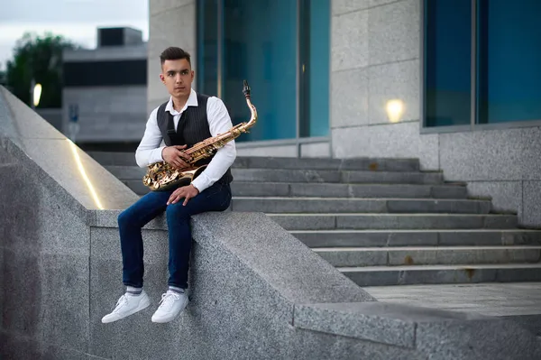 Muž saxofonista pózuje na schodech na ulici — Stock fotografie