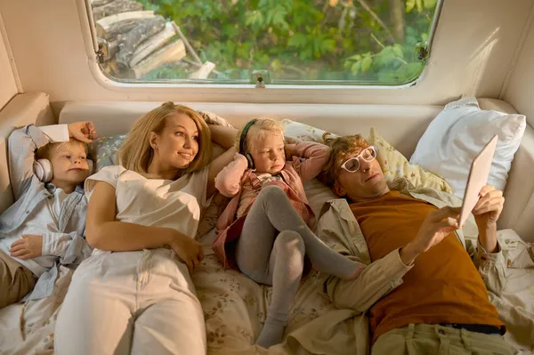 Fröhliche Familie liegt im Bett im Wohnmobil, campt — Stockfoto