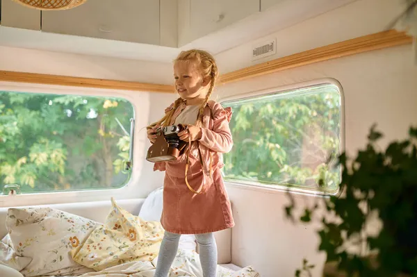 Petite fille tient caméra en camping-car, camping — Photo