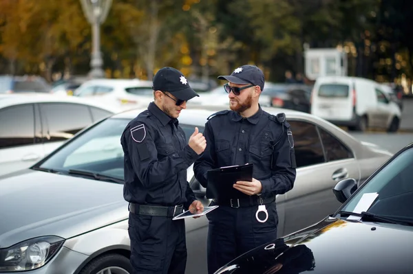 Politieagenten geven een boete uit op de parkeerplaats. — Stockfoto