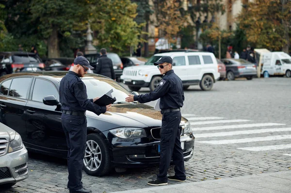 Policiais verificando veículo no estacionamento — Fotografia de Stock