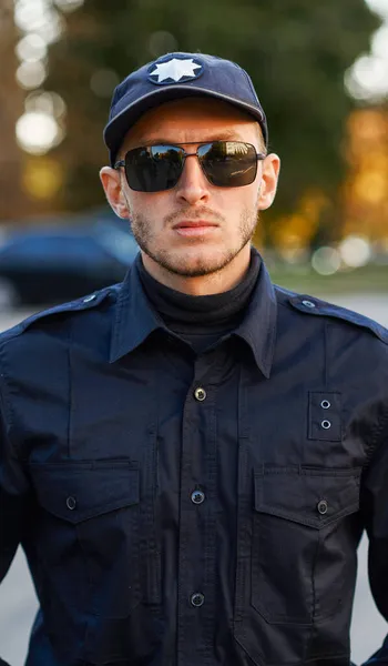 Офицер полиции позирует в форме и солнцезащитных очках — стоковое фото