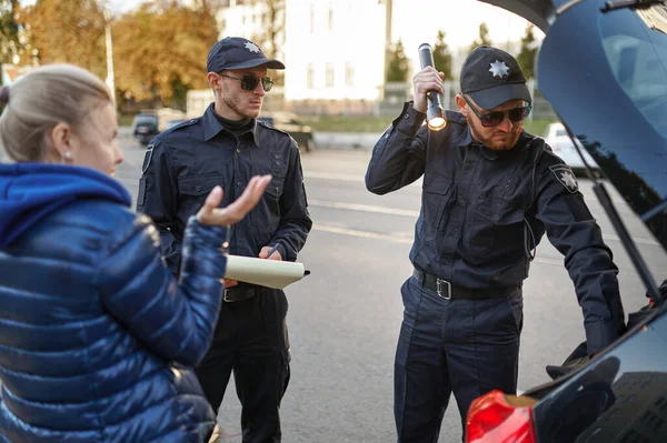 Polizeistreife kontrolliert den Kofferraum eines Autos — Stockfoto