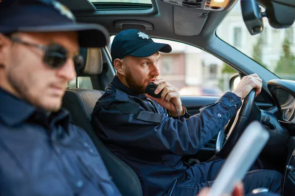 Dois policiais do sexo masculino em uniforme posa no carro — Fotografia de Stock