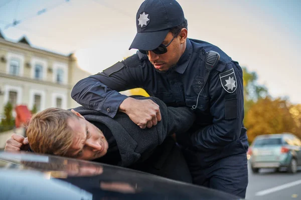 Un policier en lunettes de soleil arrête un jeune homme — Photo