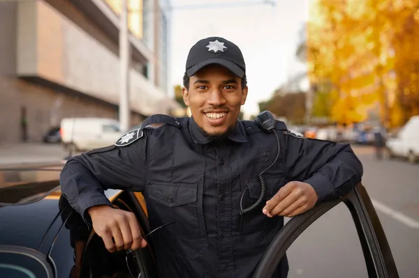 Politieagent in uniform poseert bij de patrouillewagen — Stockfoto