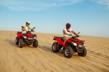 ATV 'deki kum tepelerinden iki yarışçı geliyor.