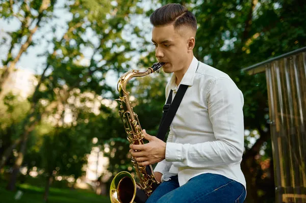 Jeune saxophoniste joue du saxophone dans le parc — Photo