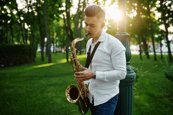 Saxophonist plays melody in summer park — Stock Photo, Image