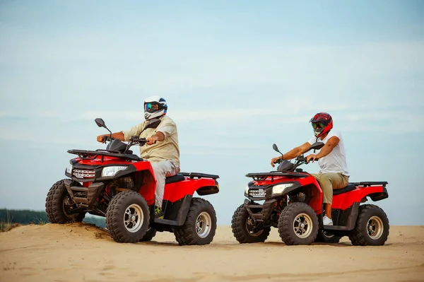 Two men in helmets, atv riding in desert sands — Stock Photo, Image