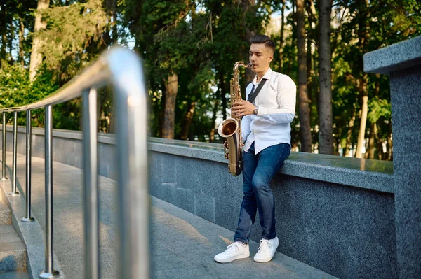 어린 색소폰 연주자 가 공원에서 색소폰을 연주하는 모습 — 스톡 사진