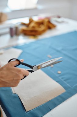 Makas tutan terzi atölyede kumaş kesiyor.