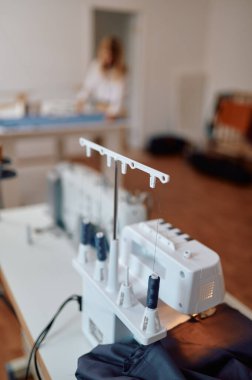 Dikiş makinesi, terzi kadın masada çalışıyor.