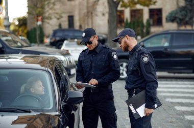 Erkek polis memurları ehliyetlerini kontrol ediyor.