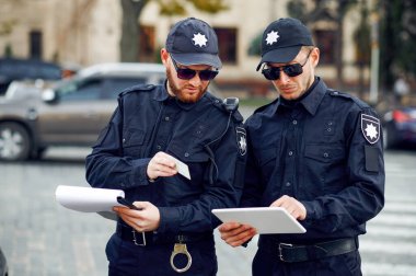 İki erkek polis memuru otoparkı kontrol ediyor.