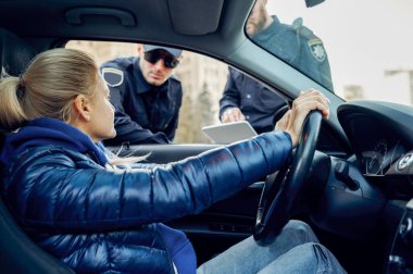İki polis memuru kadın şoförle konuşuyor.