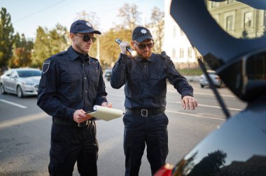 Polis devriyesi arabanın bagajını kontrol ediyor.