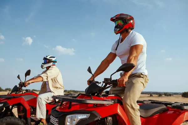 Kasklı ve gözlüklü adamlar çölde ATV 'ye biniyorlar. — Stok fotoğraf