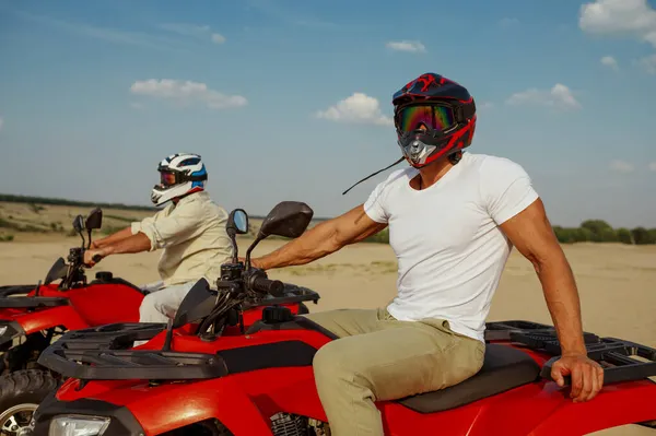 ヘルメットとメガネの男性は砂漠のatvに乗る — ストック写真