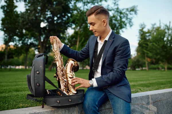 Мужчина-саксофонист забирает саксофон из чемодана — стоковое фото