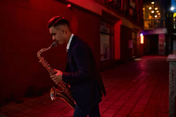 De jonge saxofonist speelt 's nachts de sax op straat — Stockfoto