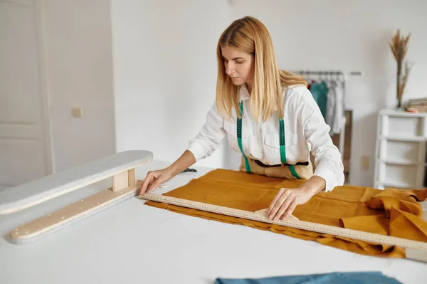 Costurera mide tela en el lugar de trabajo en taller — Foto de Stock