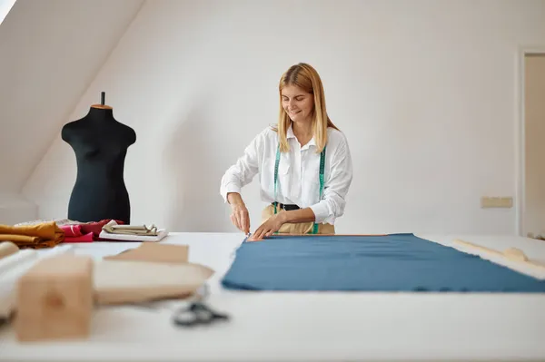 Dressmaker mide la tela en el lugar de trabajo en el taller — Foto de Stock