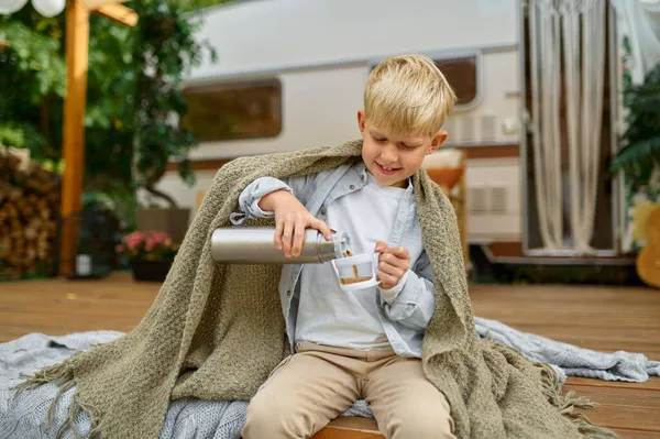 Little boy drinks tea from thermos at the trailer — Stock Photo, Image