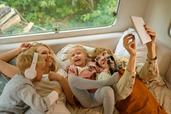 Famille gaie couchée au lit en camping-car, camping — Photo