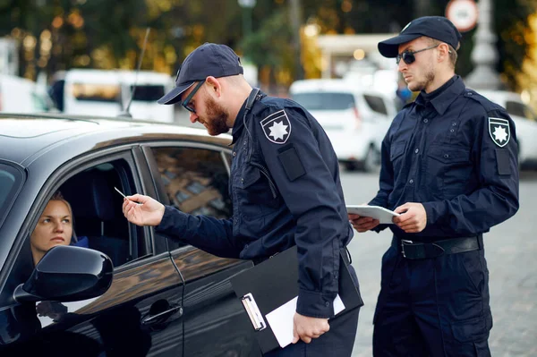 Policiais do sexo masculino verificando a carteira de motorista — Fotografia de Stock