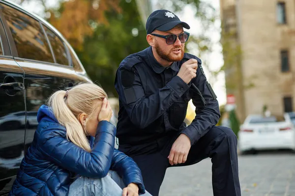 Man politieagent helpt een vrouwelijke bestuurder — Stockfoto