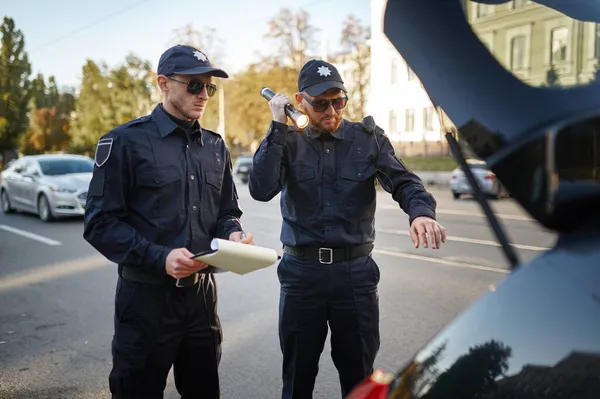 Police patrol checking the trunk of a car — Stock Photo, Image