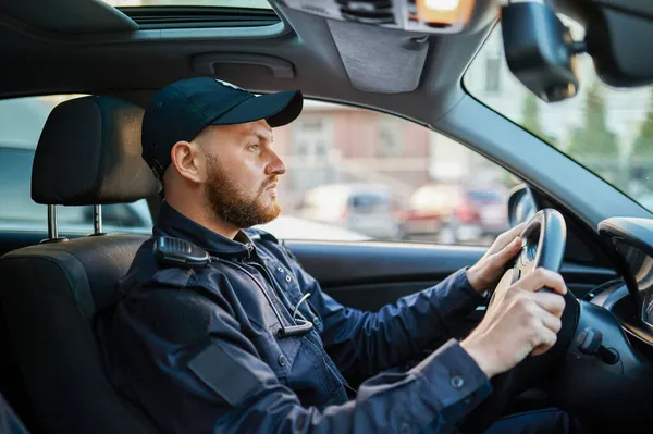 Mannelijke politieagent in uniform poseert in de auto — Stockfoto