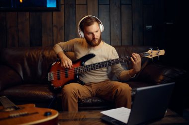 Gitar çalan adam dizüstü bilgisayara bakıyor.