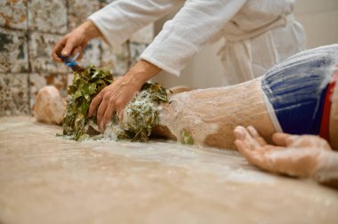 Adam banyoda süpürgeyle masaj yaptırıyor.