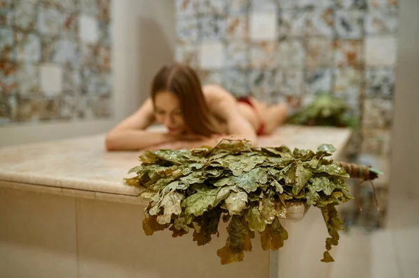 Женщина отдыхает в бане, фокусируется на метле — стоковое фото