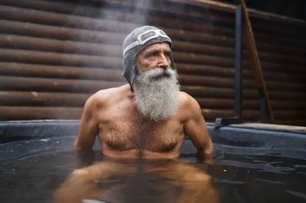 Пожилой мужчина отдыхает в ванной на улице — стоковое фото