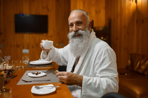 Senior man die thee drinkt rust in de sauna — Stockfoto