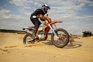 Kum tepeciğinde araba kullanan profesyonel motokros sürücüsü